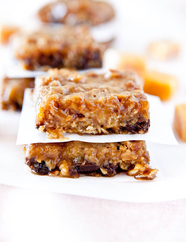 Two stacked Caramel and Chocolate Gooey Bars separated by parchment paper