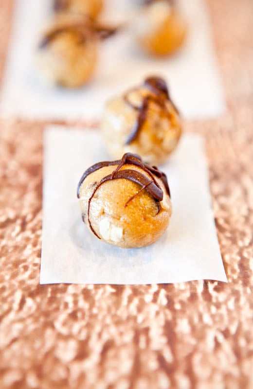 Peanut Butter Chocolate Chip Cookie Dough Bites drizzled with chocolate on parchment paper