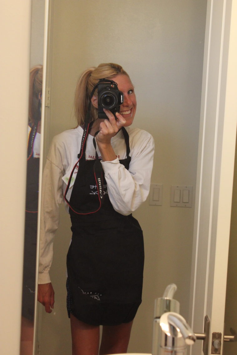 Woman taking photo of self wearing apron in mirror