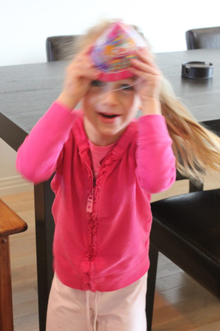 Young girl playing with birthday hat holding it to head
