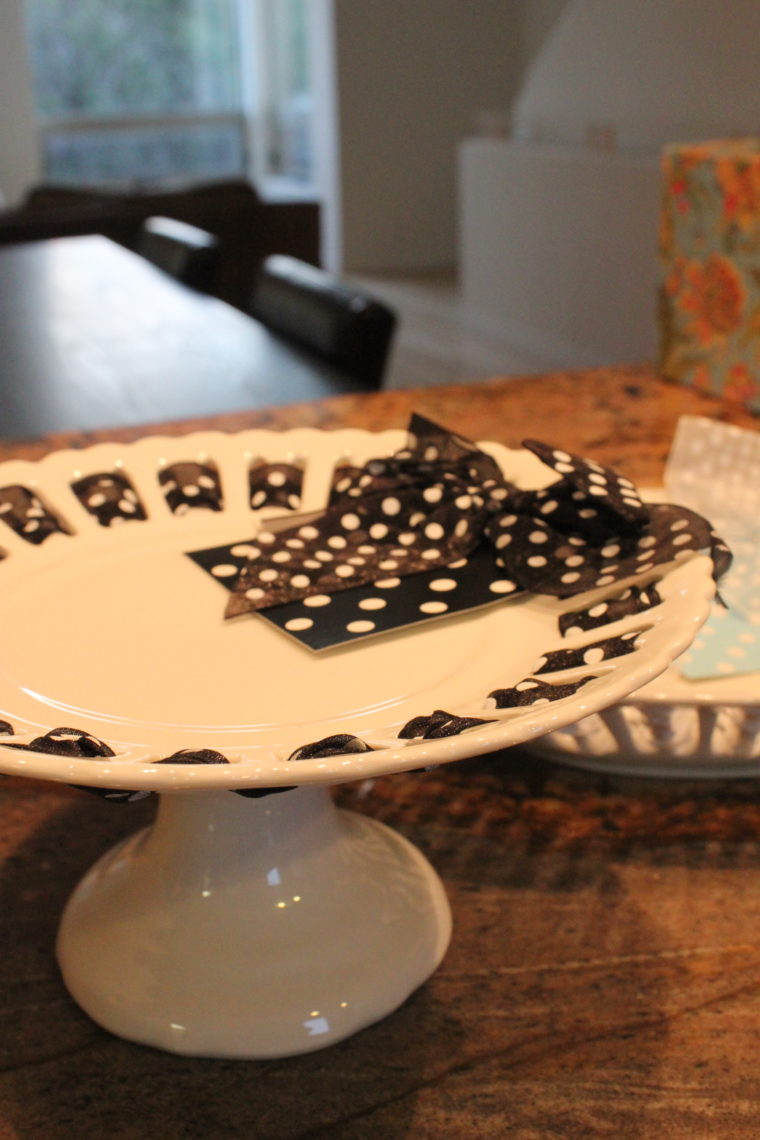 Close up of cake stand with black and white spotted ribbon