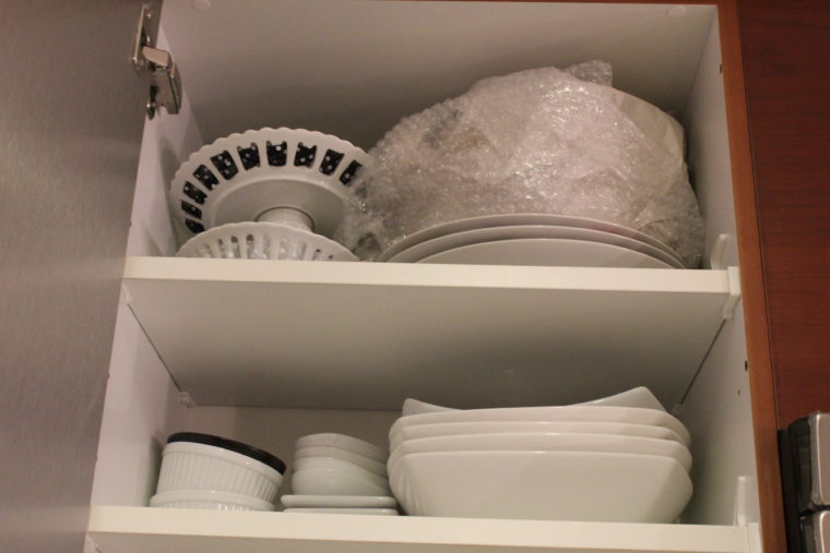 New dishes put away in kitchen cabinet 