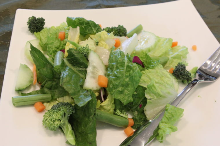 Salad with mixed vegetables on white plate with fork