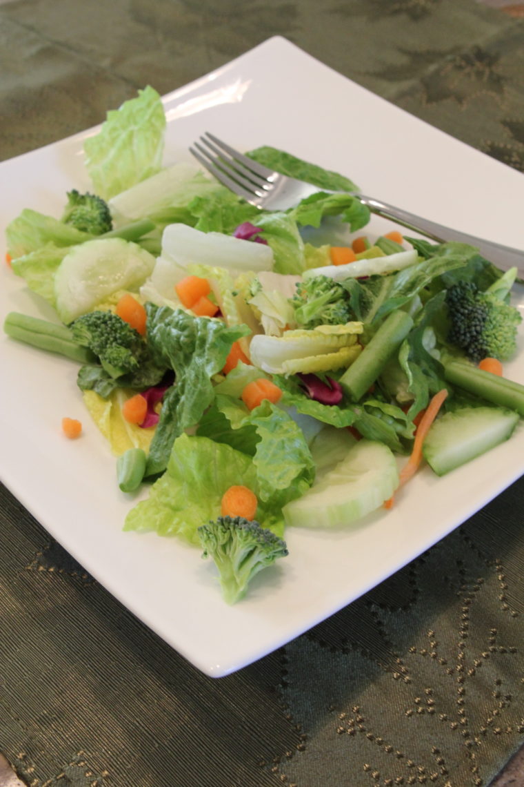 Green salad with vegetables white plate with fork