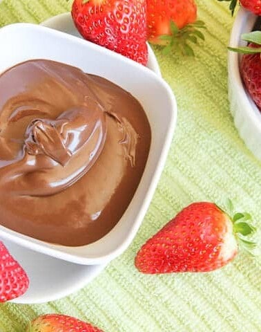 A bowl of chocolate fondue with fresh strawberries.