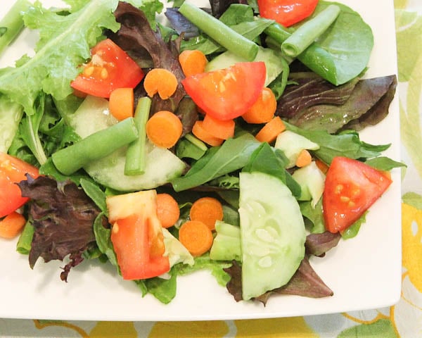Green salad with vegetables topped with Orange Coconut Lemon Pepper Vinaigrette