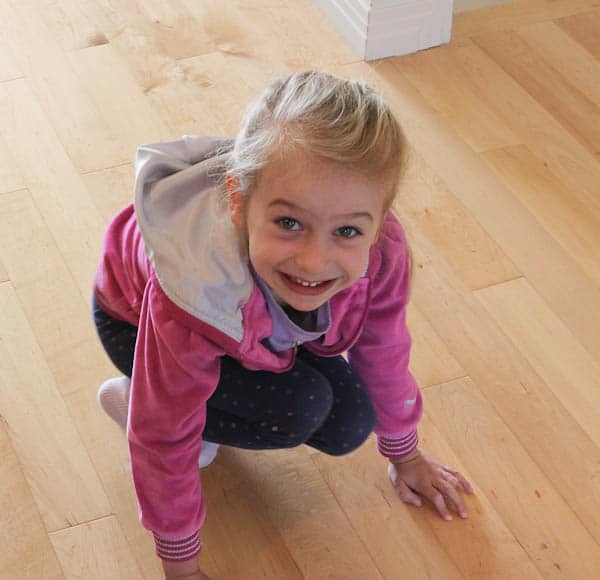 Young girl squatting down on floor smiling