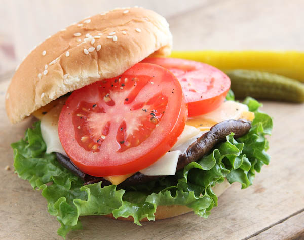 open hamburger with tomatoes, mushroom, cheese, and lettuce