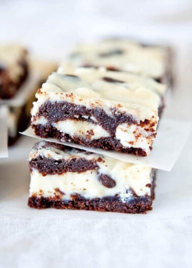 Stacked cream-filled chocolate cookie bars on a white surface.