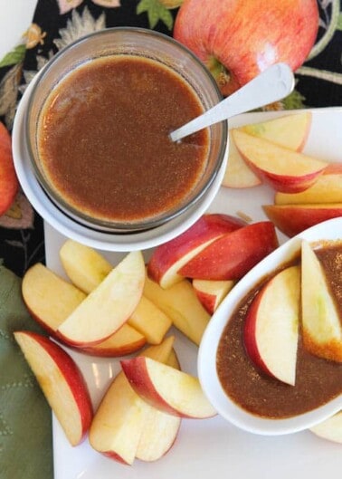 Sliced apples arranged around a jar of caramel dip.