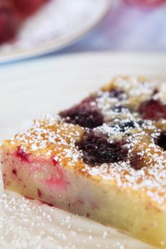 Close up of slice of Mixed Berry Clafoutis with powdered sugar