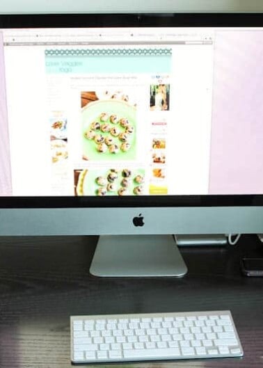 An imac computer displaying a webpage with food recipes, accompanied by a wireless keyboard and mouse on a desk.