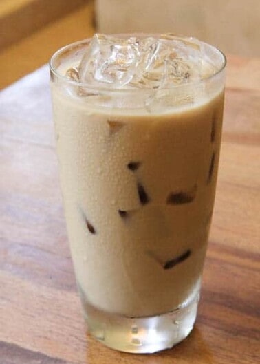 A glass of iced coffee on a wooden table.