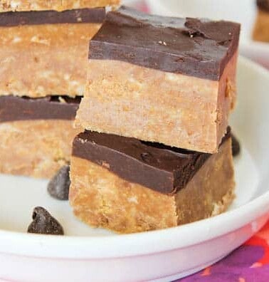 Stacked peanut butter bars with chocolate topping on a white plate.