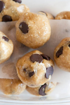Raw Vegan Chocolate Chip Cookie Dough Balls in container separated by parchment paper