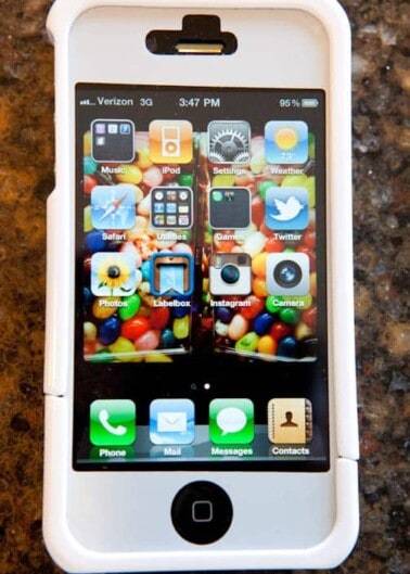 A smartphone with a white case displaying various app icons on its screen.