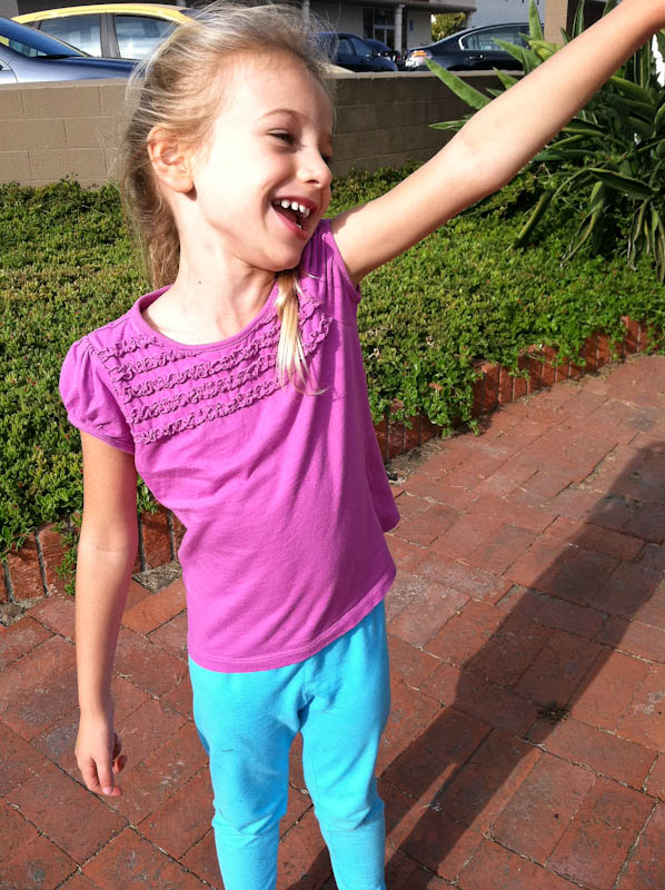 Young girl on sidewalk singing with arm up in air