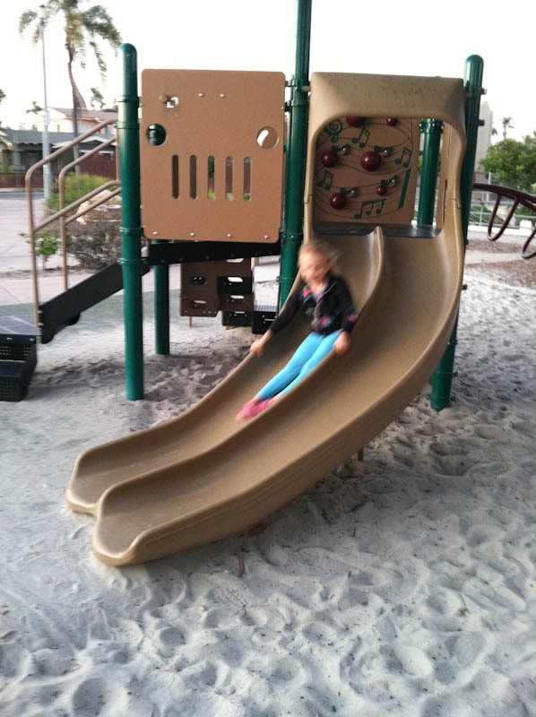 Young girl siding down slide