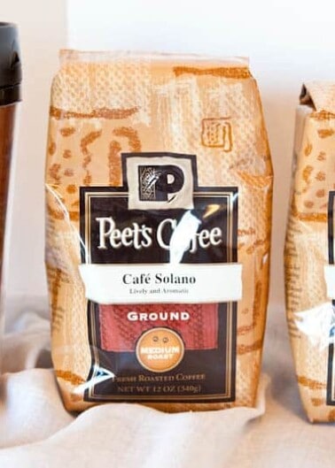 Two bags of peet's coffee & tea ground coffee with a branded tumbler.