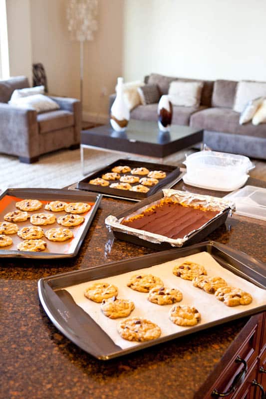 Pan of bars and three pans of cookies on marble countertop looking into living room