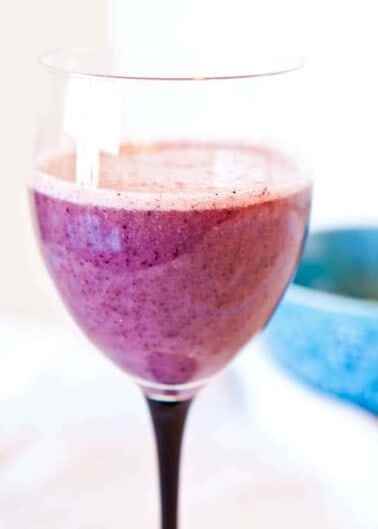 A close-up of a purple smoothie in a wine glass.