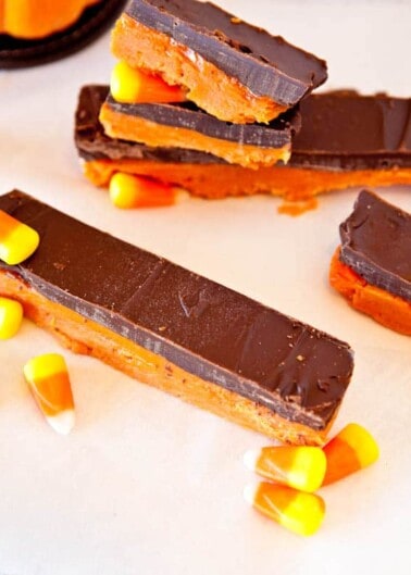 Chocolate-covered caramel bars with candy corns on a light surface.