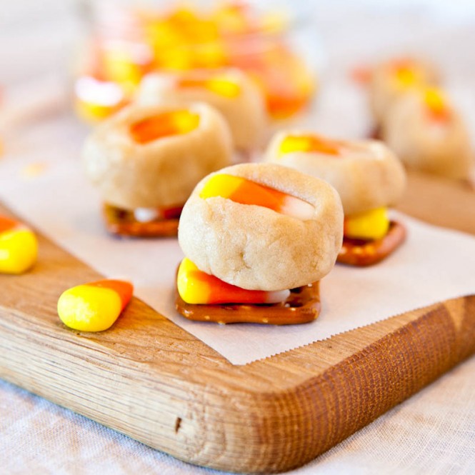 Candy Corn Cookie Dough Pretzel Bites on wood plank with candy corn around