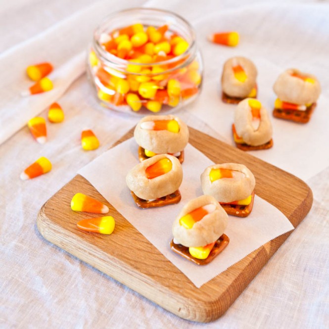 Candy Corn Cookie Dough Pretzel Bites on wood plank with candy corn around