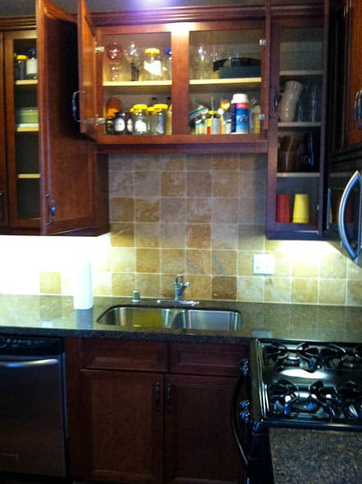 Kitchen with marble countertops and tile backsplash, filled cabinets