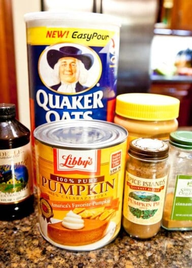 Assorted baking ingredients on a countertop, including quaker oats, canned pumpkin, vanilla extract, and spices.