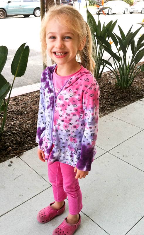 Skylar smiling on sidewalk in purple and pink sweater
