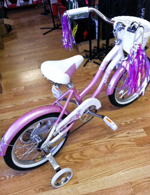Pink bicycle with white basket and pink and white streamers, white training wheels