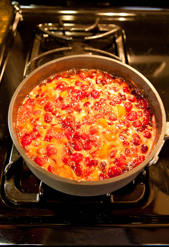 Mango and cranberries simmering in pot on stove