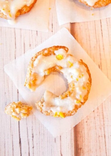 Glazed old-fashioned donut with a bite taken out, displayed on a white napkin.