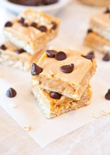 A peanut butter bar topped with chocolate chips on parchment paper.