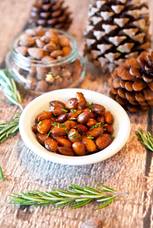 Rosemary Chipotle Roasted Almonds in white bowl with pinecones in background