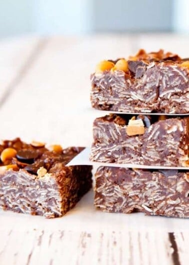 Three layered chocolate and peanut bars on a light surface.