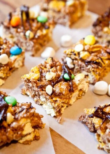 Assorted marshmallow cereal bars with chocolate drizzle and colorful candy toppings.