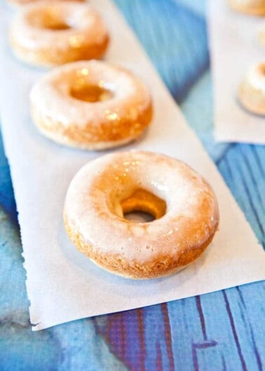 Glazed donuts on parchment paper with a blue textured background.