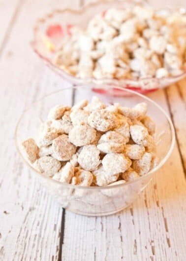 Two bowls of powdered sugar-coated snack on a wooden surface.