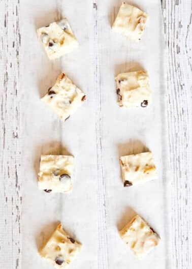 Rows of white chocolate fudge with nuts on a white cloth.