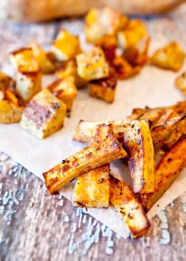 Seasoned roasted root vegetables served on parchment paper.