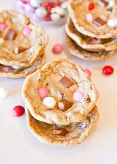 Chocolate chip cookies with colorful candy pieces on a white surface.