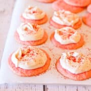 Pink cookies with a dollop of cream cheese frosting and sprinkled with red sugar.