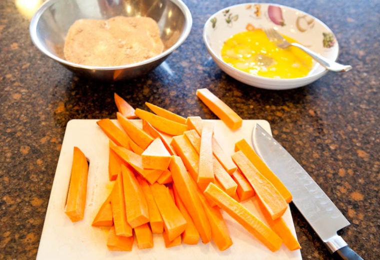 Sweet potato sticks with bowl of graham cracker crumbs and eggs