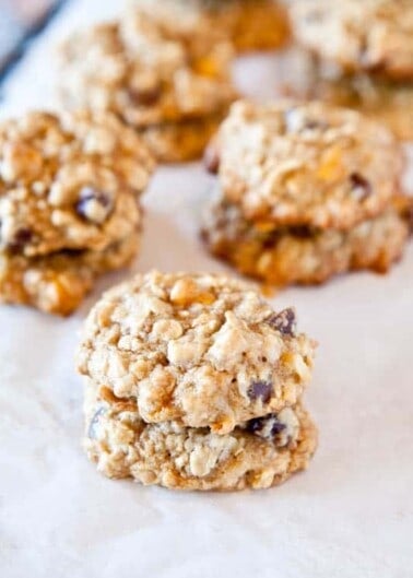 A close-up of oatmeal cookies with raisins on a parchment paper.