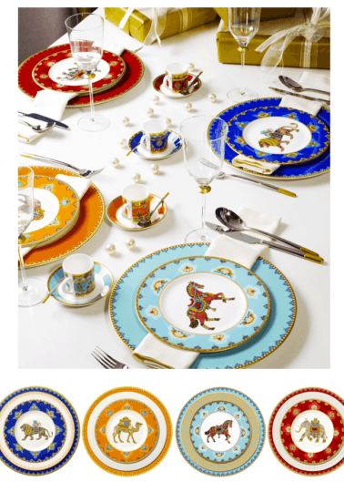 An elegantly set table with ornate tableware featuring colorful plates, cups, and gold flatware, arranged for a formal meal.