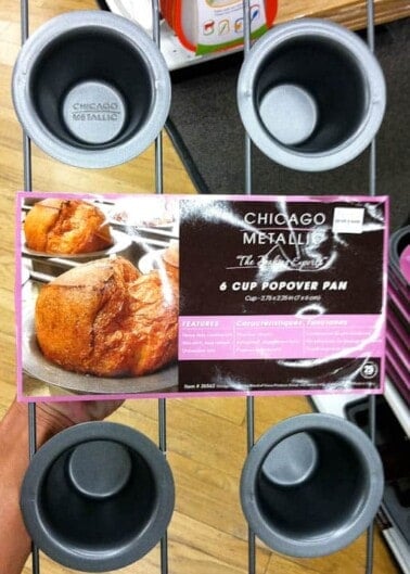 A person holding a chicago metallic 6 cup popover pan's packaging in a store aisle.