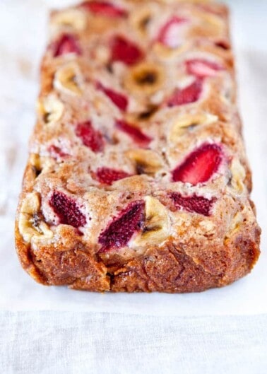 Freshly baked strawberry banana bread on a light-colored surface.