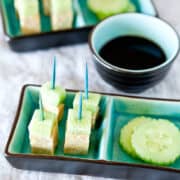 Cucumber and tofu bites with toothpick skewers served with soy sauce.
